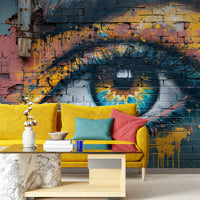 Colorful graffiti eye wall mural behind a yellow sofa in a contemporary living room