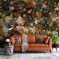 Dark floral wallpaper mural with pink, cream and orange blossoms behind a rust-colored sofa
