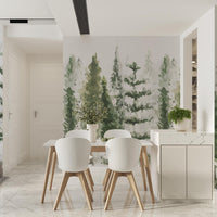Soft green pine tree wallpaper mural behind a dining table with white chairs