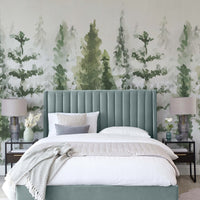 Misty pine forest wallpaper mural behind a sage green upholstered bed with white bedding