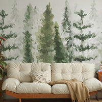 Watercolor pine tree wallpaper mural behind a cream sofa with a wooden frame