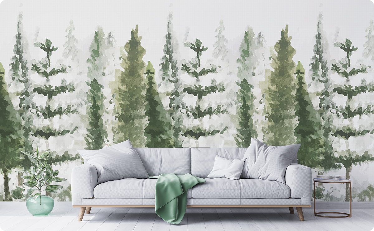 Watercolor pine tree wallpaper mural in soft green and gray behind a light gray sofa