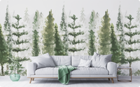 Watercolor pine tree wallpaper mural in soft green and gray behind a light gray sofa