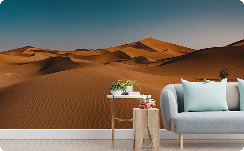 Golden desert sand dune wallpaper mural beneath a blue sky behind a light gray sofa