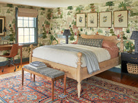 Mughal garden wallpaper surrounding a vintage bedroom with wooden bed and patterned rug